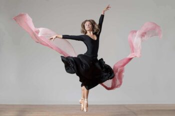 Ballet dancer en pointe in a black dress with flowing pink fabric
