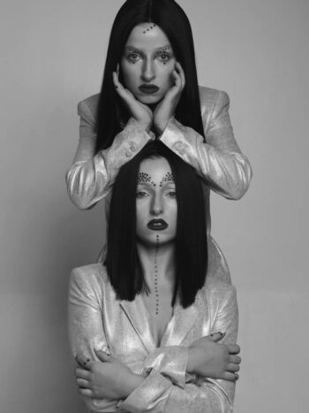 Two models with long dark hair posed one above the other, black-and-white portrait