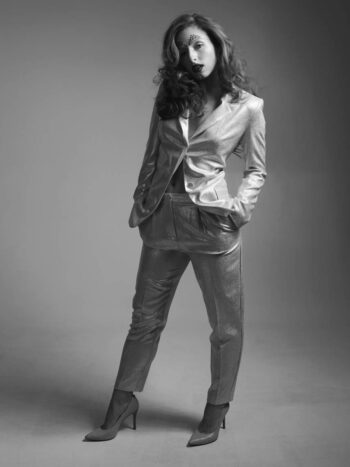 Model in a metallic suit with one hand on her hip, full-length black-and-white portrait