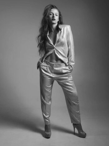 Model in a metallic suit with hands in pockets, full-length black-and-white portrait