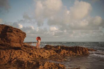 Schaeffer Studios Fashion Photographer Featuring Zorelys Lisboa in Large Hat by Rocks and Ocean